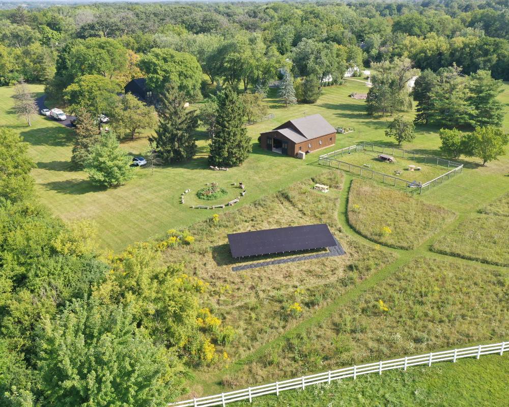 View from far away of the barrington hills home, barn and ground installation of solar panels