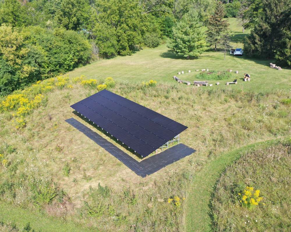 View of a solar panel installed on the ground near a barrington hillls home